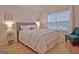 Bright primary bedroom featuring hardwood floors, queen bed, and accent chair at 150 Butterton Ct, Fayetteville, GA 30214