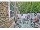 Cozy outdoor patio with stone siding, four chairs, and a green patterned rug for relaxing and entertaining at 150 Butterton Ct, Fayetteville, GA 30214