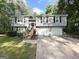 Split-level home featuring a two-car garage, wood staircase, black shutters, and gray siding at 5405 Lakeside Dr, Union City, GA 30291