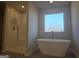 Modern bathroom features a standalone tub, separate shower with white subway tile, and a large window at 1672 Fuma Leaf Way Rd, Mcdonough, GA 30253