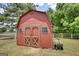 Exterior of a barn with a rustic red finish, wooden doors, and a small window, surrounded by a grassy yard at 1024 Bethany Rd, Covington, GA 30016