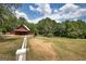 A long dirt driveway leads to a red barn and outbuildings, all enclosed by a white fence at 1024 Bethany Rd, Covington, GA 30016
