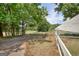 View of a long driveway, white fencing, mature trees, and a glimpse of the surrounding landscape at 1024 Bethany Rd, Covington, GA 30016