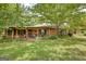Traditional brick home with inviting front porch seating, lush landscaping, and shaded by large trees at 1024 Bethany Rd, Covington, GA 30016