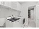Bright laundry room with a modern washer and dryer, overhead cabinets, and easy access to closet at 229 Widener Way, Peachtree City, GA 30269