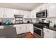 Kitchen featuring white cabinets, stainless steel appliances, black countertops, and hardwood floors at 1478 Interlaken Pass, Jonesboro, GA 30238