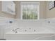 Relaxing bathroom with a large soaking tub, jet tub, and bright natural light at 229 Lafayette St, Locust Grove, GA 30248