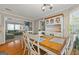 Sunlit dining area with a stylish wooden table and chairs, built in hutch, and access to a comfortable living room at 229 Lafayette St, Locust Grove, GA 30248
