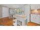 Bright and airy kitchen featuring a center island, hardwood floors, a dining table and chairs, and modern appliances at 229 Lafayette St, Locust Grove, GA 30248