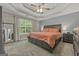 Spacious main bedroom with a tray ceiling, ceiling fan, and large windows at 229 Lafayette St, Locust Grove, GA 30248