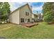 Backyard showing lawn and rear of a light yellow townhome with a wooden deck at 737 Shadow Lake Dr, Lithonia, GA 30058