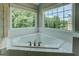 Close up of garden tub featuring tile, large windows, and stainless steel hardware at 823 Hennepin Ter, Mcdonough, GA 30253