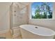 Modern bathroom showcasing a standalone tub, frameless glass shower, and a large window at 207 Tiverton Trl, Peachtree City, GA 30269