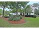 Manicured lawn and mature trees surround this two-story home, with a lush garden in front at 207 Tiverton Trl, Peachtree City, GA 30269