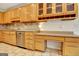 Well-lit kitchen featuring wood cabinets, stainless steel appliances, and a built-in desk area at 207 Tiverton Trl, Peachtree City, GA 30269