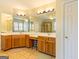 Bright bathroom featuring a double vanity with wood cabinets and a large mirror with decorative lighting at 2810 Promenade Pl, Buford, GA 30519