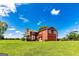 Expansive yard with two-story red home, surrounded by lush green space on a sunny day at 68 Riveree Rd, Brooks, GA 30205