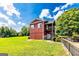 Red home with metal roof, balcony, stone accents, and surrounded by a green lawn under a bright blue sky at 68 Riveree Rd, Brooks, GA 30205