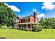 Lovely front exterior showcases the home's two-story facade with a stone chimney and cozy front porch at 68 Riveree Rd, Brooks, GA 30205