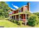 This well-maintained red home features a stone chimney, a covered front porch, and neat landscaping at 68 Riveree Rd, Brooks, GA 30205