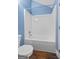 Bathroom featuring a white bathtub and shower combination, toilet, blue walls and dark wood-look flooring at 441 Crumbley Rd, Mcdonough, GA 30252