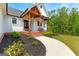 Detailed view of a covered front porch with wood beams, brick stairs, and manicured landscaping at 155 Grace Hope Dr, Brooks, GA 30205