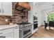Elegant kitchen featuring stainless steel appliances, a brick backsplash, and pristine white cabinetry with dark hardware at 155 Grace Hope Dr, Brooks, GA 30205