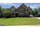 Beautiful two-story home with a stone facade, manicured lawn, and driveway at 8340 Nolandwood Ln, Villa Rica, GA 30180