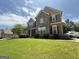 Charming two-story home featuring a stone facade, manicured lawn, and inviting front porch at 8340 Nolandwood Ln, Villa Rica, GA 30180