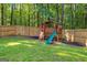 A charming wooden playhouse with a slide sits in a beautiful, fenced backyard with plenty of green space at 111 Rosignol Dr, Sharpsburg, GA 30277