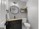 Stylish half bathroom featuring a round mirror, black vanity with granite countertop, and modern fixtures at 111 Rosignol Dr, Sharpsburg, GA 30277