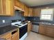 Galley kitchen featuring wooden cabinetry, black appliances, and a window view at 132 Scarlett Place Dr, Bowdon, GA 30108