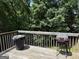 Back deck featuring a wooden railing and an old charcoal grill, surrounded by lush trees at 1432 Eagles Nest Cir, Carrollton, GA 30116