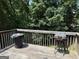 Back deck featuring a wooden railing and an old charcoal grill, surrounded by lush trees at 1432 Eagles Nest Cir, Carrollton, GA 30116