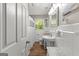 Bright bathroom with white tiled walls, pedestal sink, and wood-look flooring at 204 First St, Bowdon, GA 30108