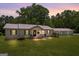 Charming single-story home at dusk featuring a metal roof, neutral siding, well-manicured lawn, and detached garage at 204 First St, Bowdon, GA 30108