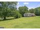 Scenic view of home surrounded by a large green lawn and mature trees at 204 First St, Bowdon, GA 30108