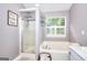 Bright bathroom features a shower, soaking tub under a window, and shelving at 5765 Woodstone Dr, Cumming, GA 30028