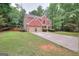 Two-story brick home showcasing a lush green lawn, a long driveway and mature trees creating a private setting at 5765 Woodstone Dr, Cumming, GA 30028
