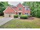 Charming two-story red brick home featuring a manicured lawn and a two-car garage, nestled among mature trees at 5765 Woodstone Dr, Cumming, GA 30028