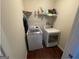 A small laundry room with wood floors, front-loading washer and dryer, and a shelf at 5470 Hilltop Pass, Fairburn, GA 30213