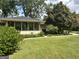 Lawn view of the home's exterior with an enclosed porch and mature trees at 2334 Connally Dr, East Point, GA 30344