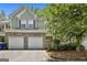 Charming townhome featuring a two-car garage with stone accents, mature landscaping, and neutral siding at 508 Las Brasis Ct, Peachtree City, GA 30269