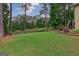 Lush backyard with a large grassy area, mature trees, and manicured landscaping at 405 Woodbrook Way, Lawrenceville, GA 30043