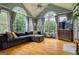 Sunroom living room featuring hardwood floors, many windows, vaulted ceiling and a gray sectional sofa at 405 Woodbrook Way, Lawrenceville, GA 30043