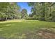 Large grassy lot surrounded by mature trees under a clear blue sky, perfect for building a dream home at 288 Winthrop Dr, Sharpsburg, GA 30277