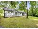 A spacious backyard with lush greenery, mature trees, and the rear of the house in the background at 312 Iron Horse Way, Stockbridge, GA 30281