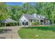 Home exterior view with an attached porte-cochere, patio, and a well-maintained lawn surrounded by mature trees at 1572 Hines Rd, Moreland, GA 30259