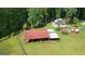 Aerial view of a red and silver outbuilding on a lush green lawn in a wooded surrounding at 1572 Hines Rd, Moreland, GA 30259