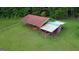 Outbuilding featuring a red metal roof and an open carport area with equipment parked underneath at 1572 Hines Rd, Moreland, GA 30259
